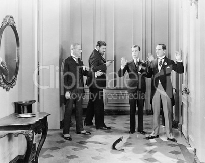 Well dressed men being held up with guns by two other men