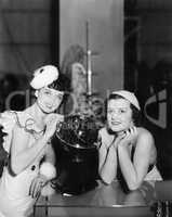 Two women posing next to a globe