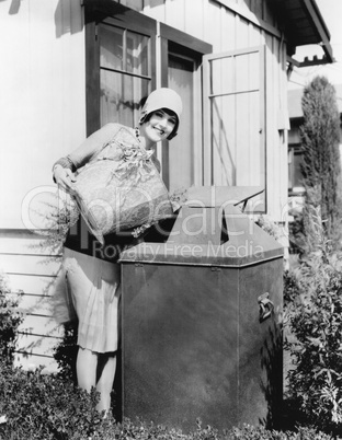 Young woman putting garbage into a garbage can
