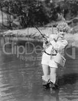 Young woman wearing waders holding a fishing rod