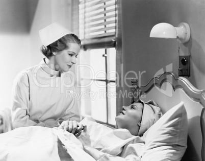 Nurse comforts a patient in a hospital bed, talking to each other