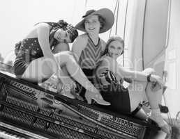 Three women sitting on top of a piano