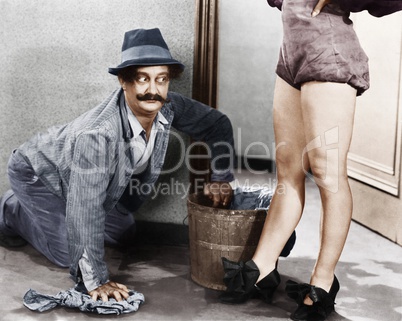 Man cleaning the floor looking at the legs of a woman