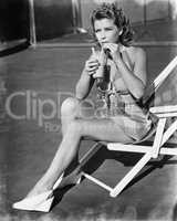 Young woman sitting on sling chair, sipping a drink