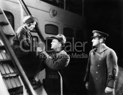 Two men talking to a young woman sitting on the ship's step