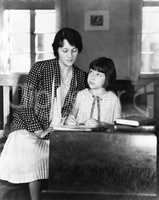 Girl sitting with her teacher in a class room