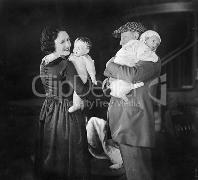 Father holding baby and mother holding a doll