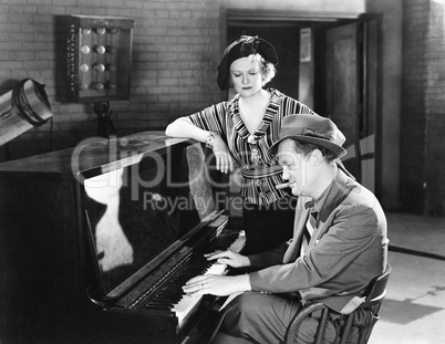 Man playing the piano while a woman is listening