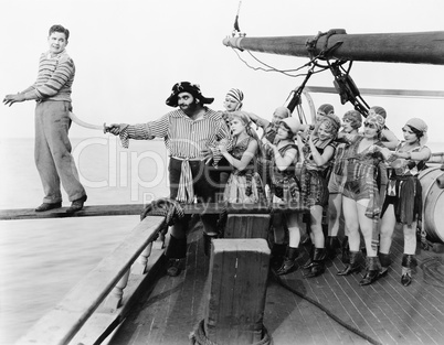 Group of pirates trying to push a young man over a plank