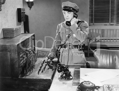 Officer talking on a telephone next to a switchboard