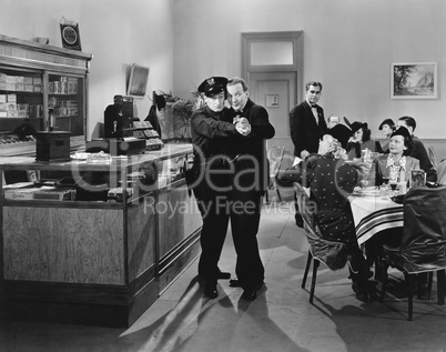 Policeman and a man dancing a tango in a restaurant