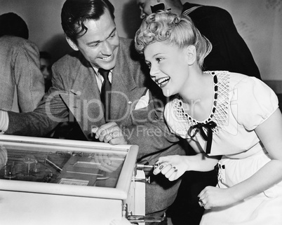 Couple having fun and laughing next to a pinball machine