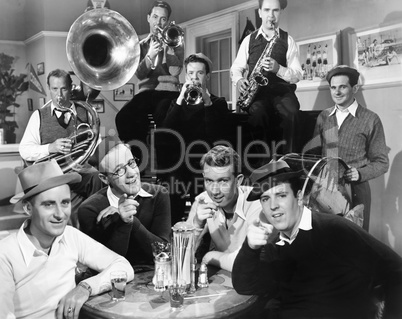 Group of men sitting in a diner with musicians behind them