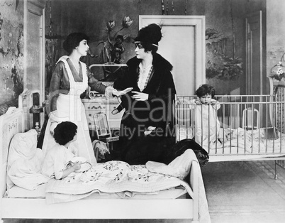 A woman with her nanny and two children in a bedroom talking with each other