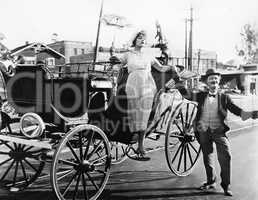 Man helping a woman get out of a wagon