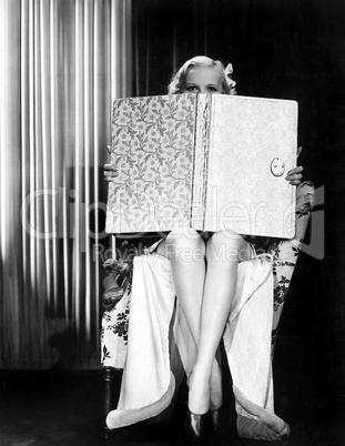 Young woman looking over top of an oversized book