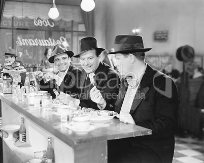 Three men sitting at the counter of a diner