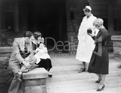 Parents with their new baby in front of the hospital being photographed