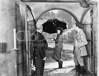 Young woman leaving a house with an umbrella to walk in the rain