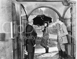 Young woman leaving a house with an umbrella to walk in the rain