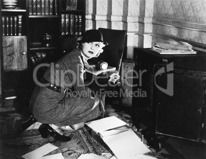 Young woman in an office next to a safe, looking over her shoulder