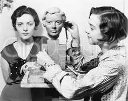 Women and an artist standing together while one is working on a bust