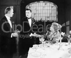 Young man greeting a couple at the dinner table