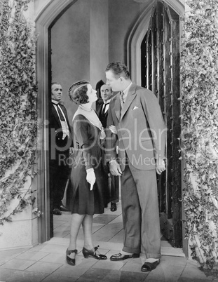 Couple standing in front of a door and having a fight