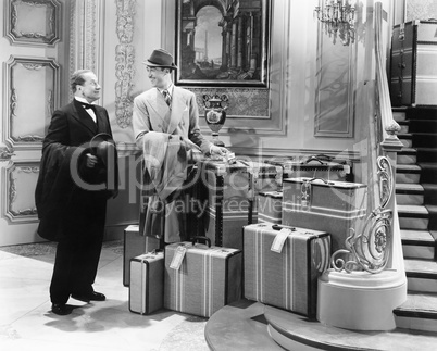Two men standing in the hallway with many suitcases
