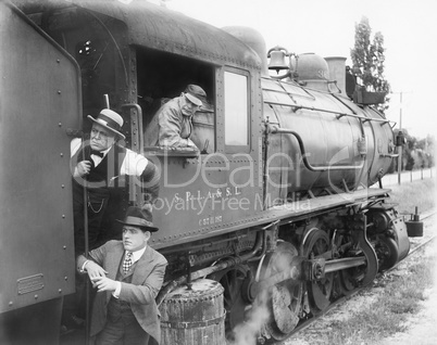Three men waiting at a steam locomotive