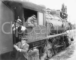 Three men waiting at a steam locomotive