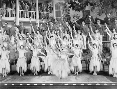 Group of dancers standing on a stage with their arms in the air and a drink in their hands