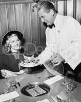 Waiter serving food to a woman at a restaurant