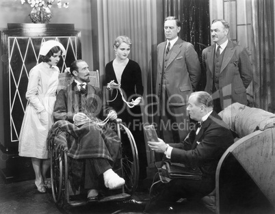 Man in a wheel chair with a broken foot and a group of people