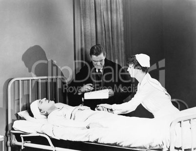Doctor and nurse attending to a patient in a hospital bed