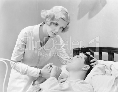 Nurse consoling a man in a hospital bed