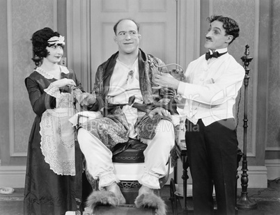 Man wearing furry slippers being pampered by two servers