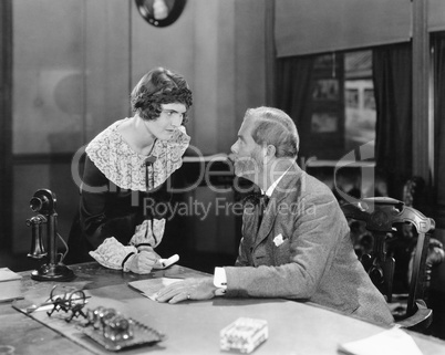 Woman with fist clenched in an office glaring at her boss