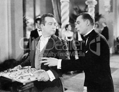 A waiter and patron at a gala event