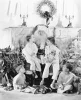 Santa Claus with presents and a group of children in front of a fire place