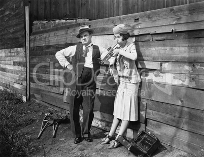 Woman practicing her trumpet while a man is standing next to her looking annoyed