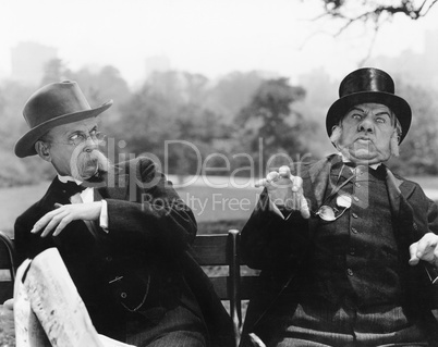 Two men sitting on a bench looking shocked