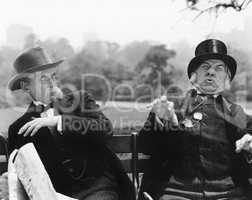 Two men sitting on a bench looking shocked