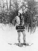 Young woman walking with snow shoes through the woods