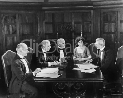 Group of men sitting with a young woman in a boardroom