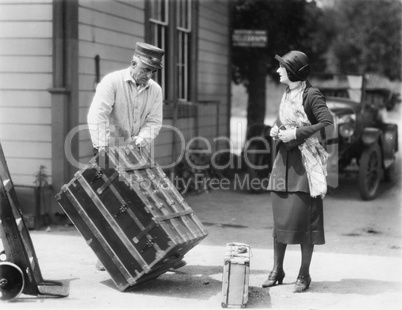 Woman and a porter carrying her trunk