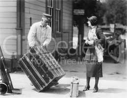 Woman and a porter carrying her trunk
