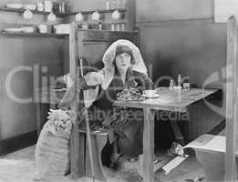 Young woman sitting in a booth in a diner, trying to steal something out of a jute bag