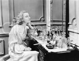Woman sitting at her vanity looking into the mirror