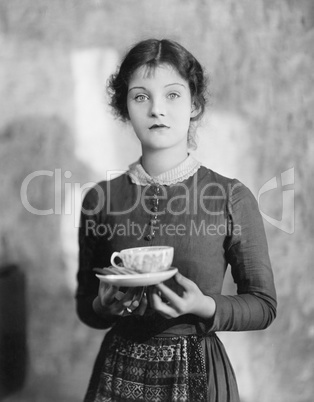 Woman standing with a cup of tea resting on her fingers